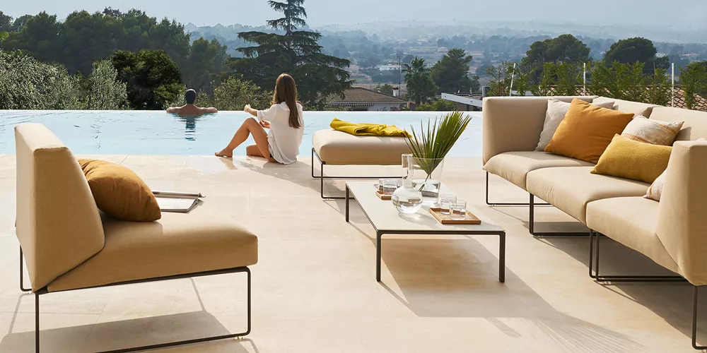 Andreu World Siesta Lounge-Set in Beige auf Terrasse mit Poolblick, entspannte Atmosphäre, moderne Outdoor-Möbel.