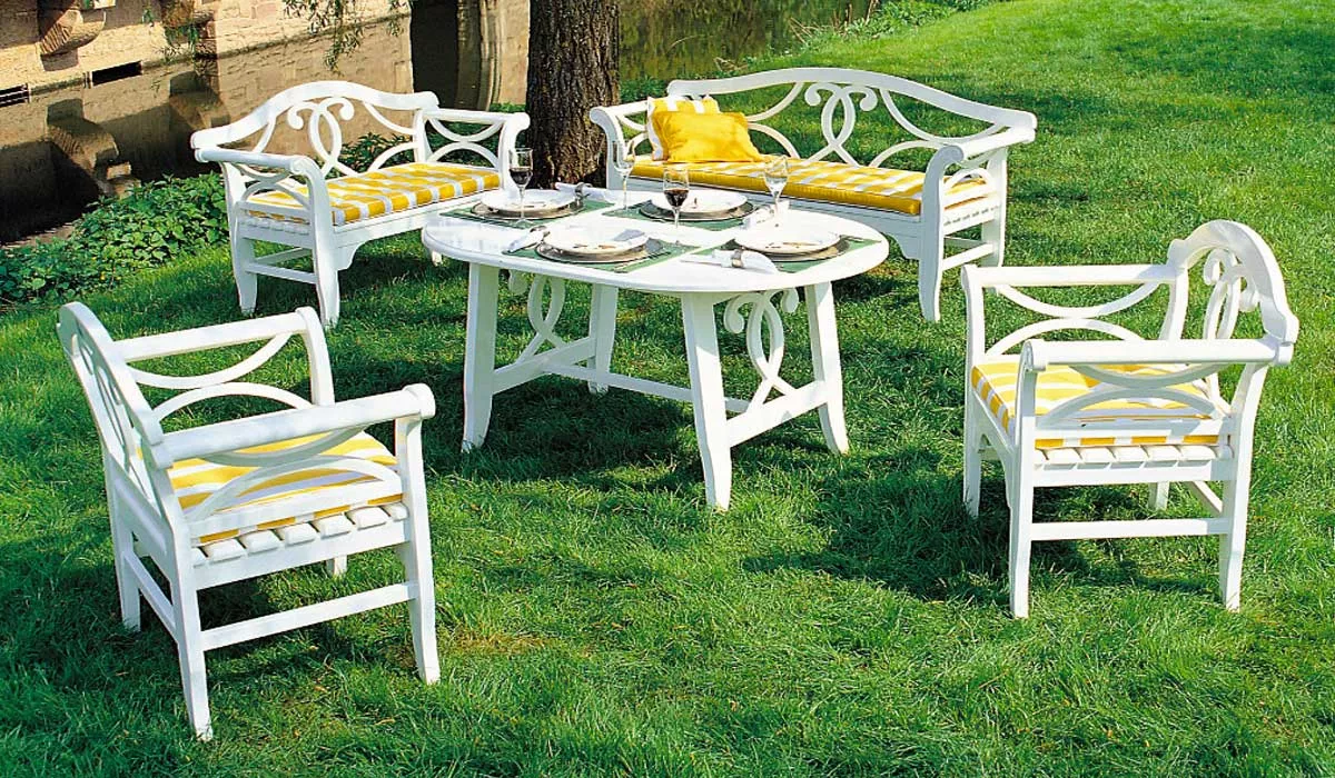 Herrenhaus Nicole Essgruppe in Weiß mit gelben Kissen, bestehend aus Tisch, zwei Stühlen und zwei Bänken, auf grünem Rasen.