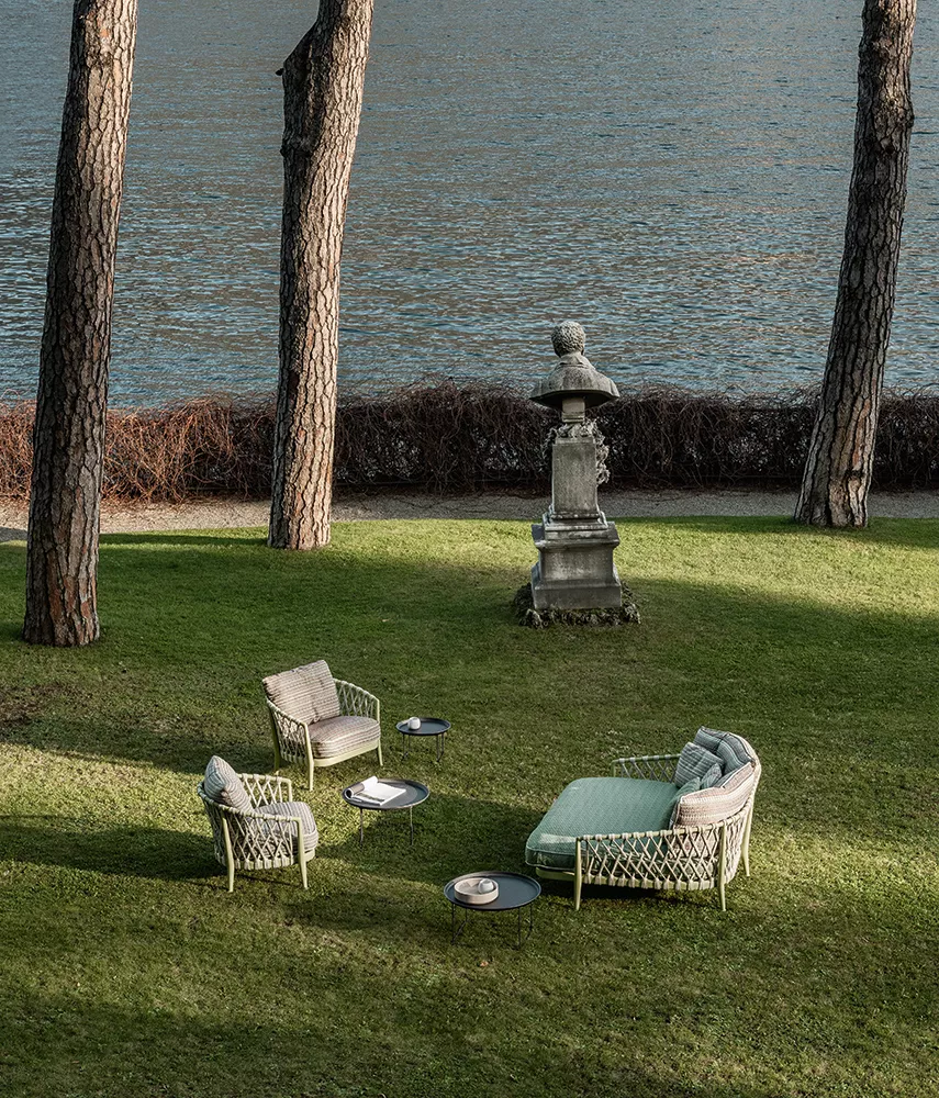 B&B Italia Erica 19 Outdoor Lounge auf einer grünen Wiese am Seeufer mit Bäumen und einer Statue im Hintergrund