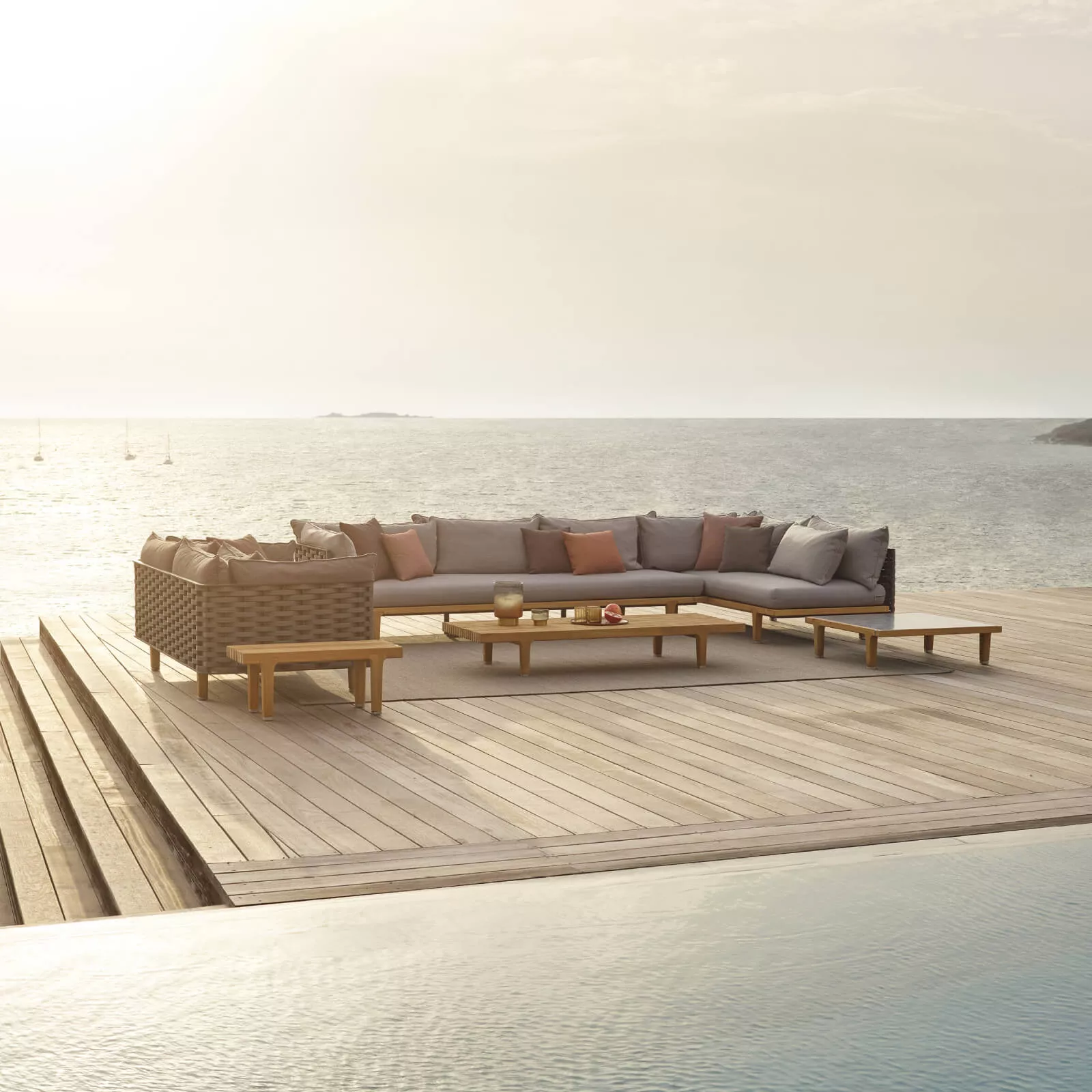 Dedon Sealine Kollektion Lounge-Sofa auf einer Terrasse mit Meerblick und Sonnenuntergang im Hintergrund 