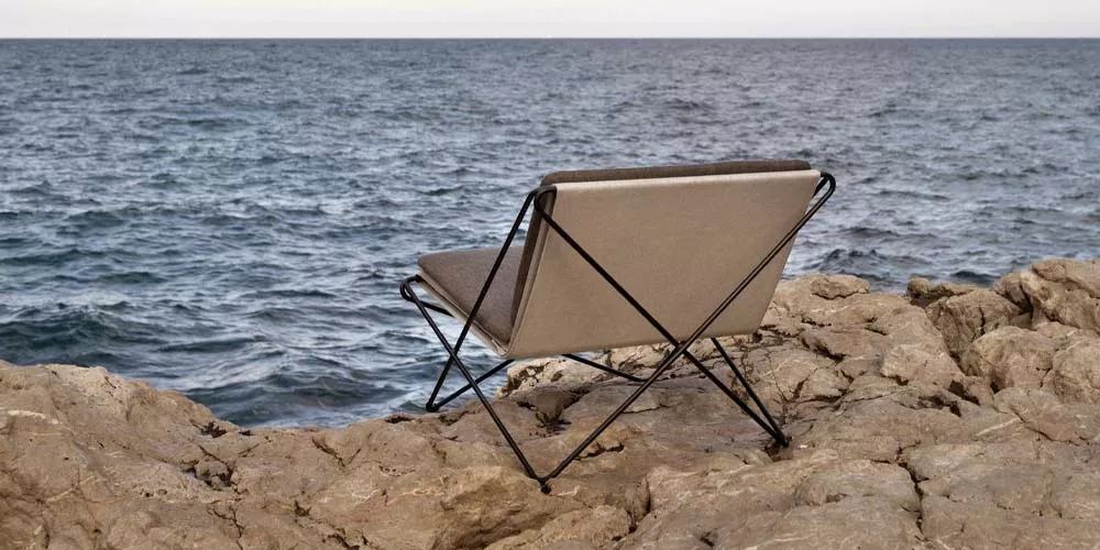 Calma Outdoor-Leuchten in Beige auf Felsen am Meer, stimmungsvolles Bild mit Blick auf die Weite des Ozeans.