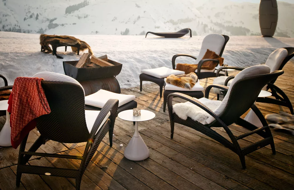 Dedon Satellite Esstisch rund 40 cm auf einer Terrasse im Schnee umgeben von Liegestühlen und einem Feuerkorb