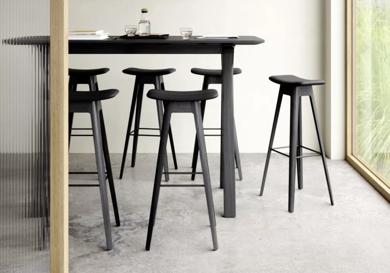 Barhocker-Kollektion von Villa Schmidt in Schwarz, aus Holz, in modernem Esszimmer mit Betonboden und Glaswand im Hintergrund.
