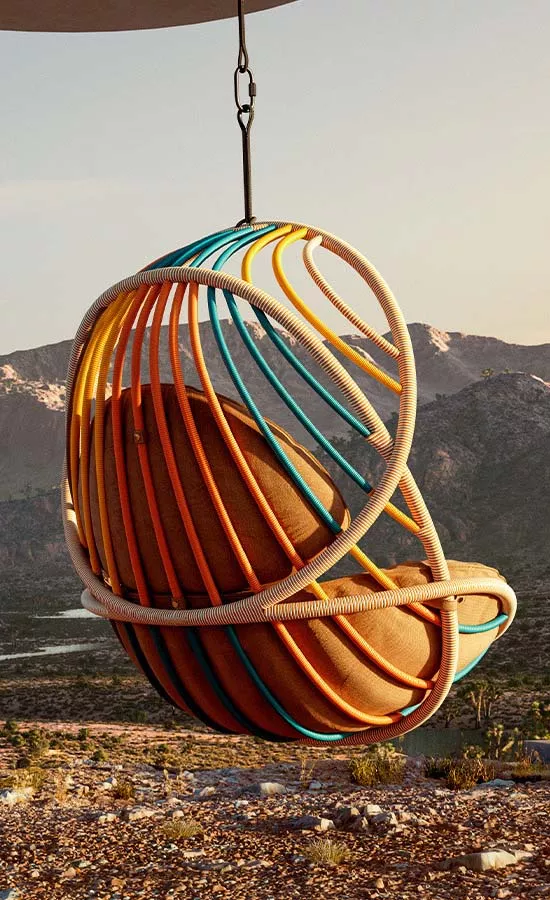 Dedon Kida Hängesessel in bunten Farben hängt vor einer Berglandschaft in der Abenddämmerung