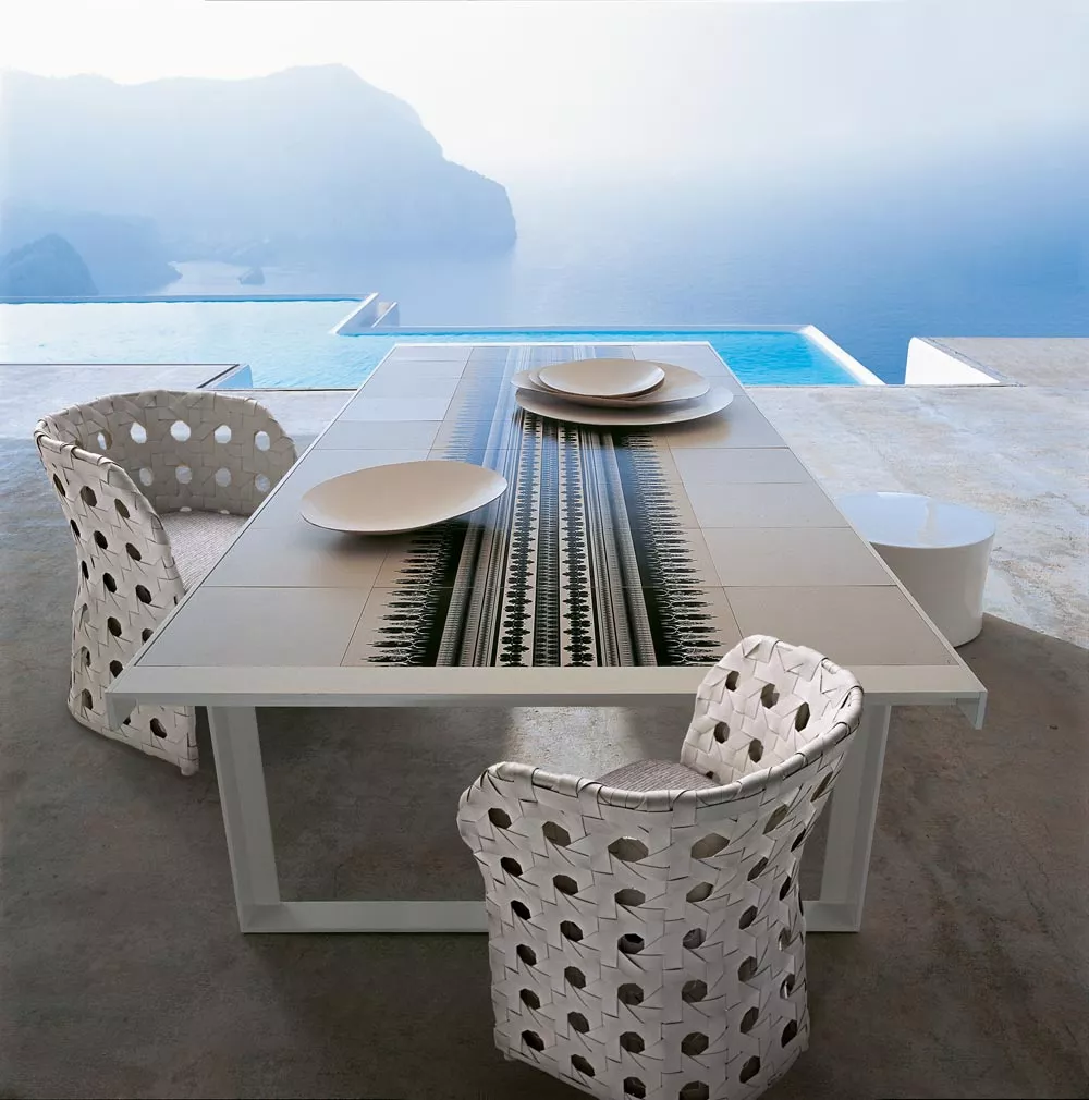 B&B Italia Canasta Outdoor Essgruppe auf einer Terrasse mit Blick auf das Meer und einem modernen Tisch mit dekorativen Tellern und Stühlen