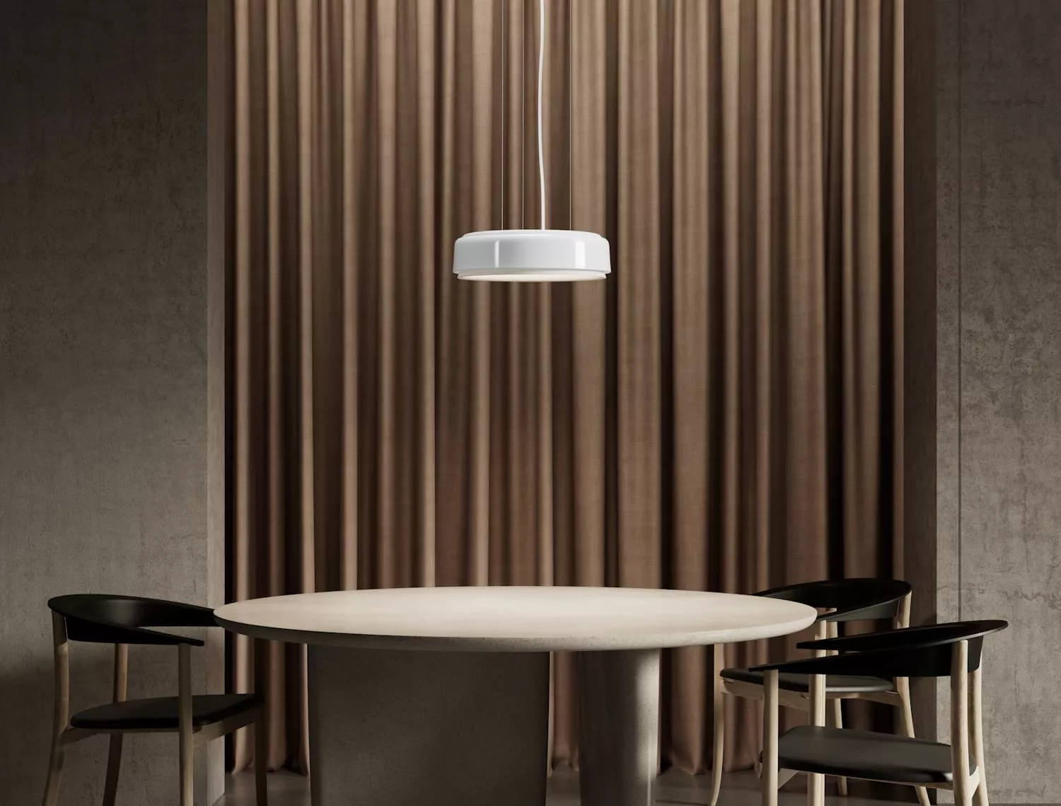 Runder Tisch mit drei schwarzen Stühlen vor braunem Vorhang, beleuchtet von einer weißen Pendelleuchte, in modernem Ambiente.