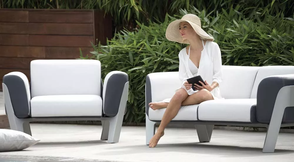 EGO Paris Bienvenue Loungegruppe in Weiß und Grau, stimmungsvolles Bild am Pool mit Frau in Sommerkleidung, entspannte Atmosphäre.