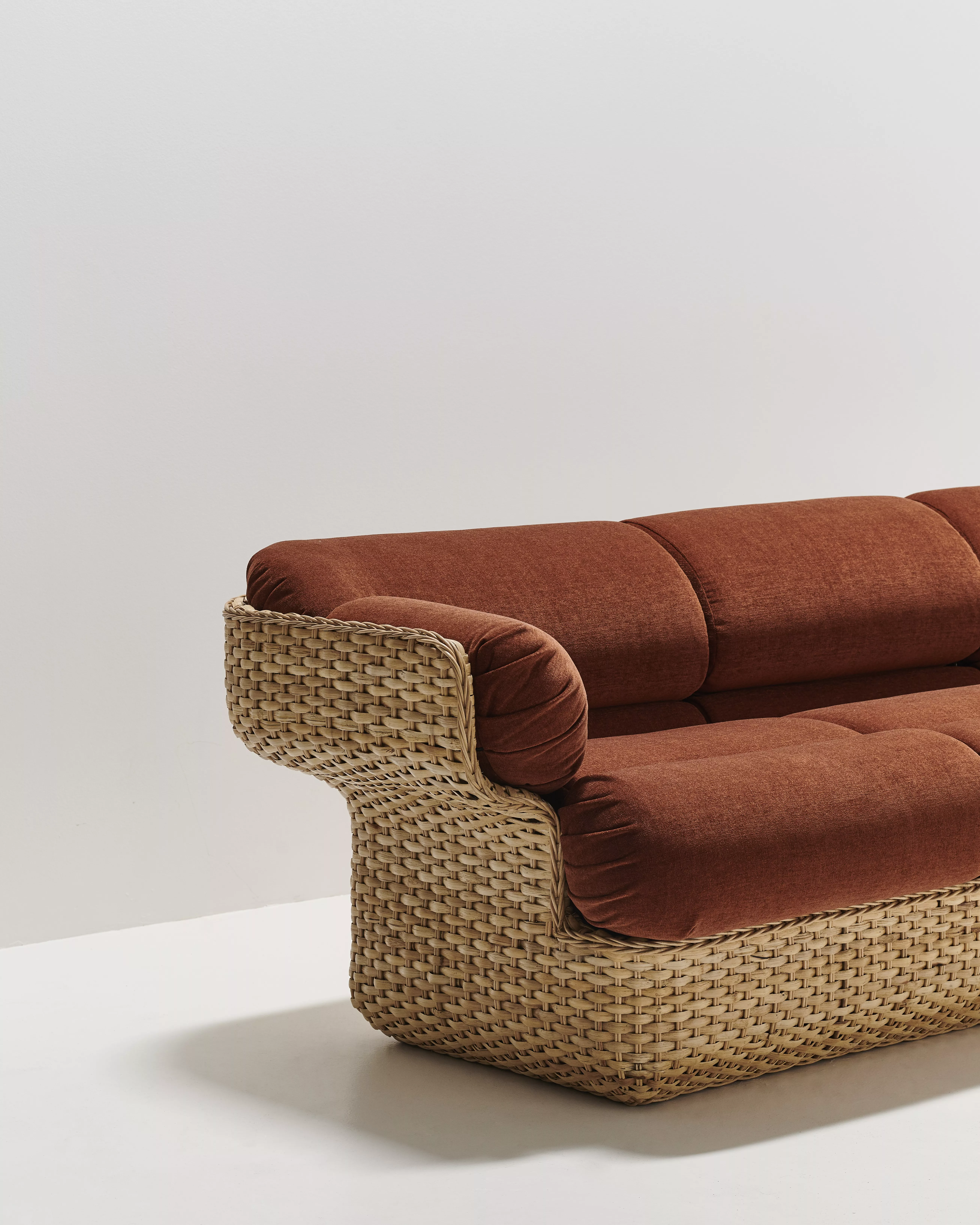 GUBI Basket Sofa in Braun mit Rattanrahmen auf weißem Hintergrund