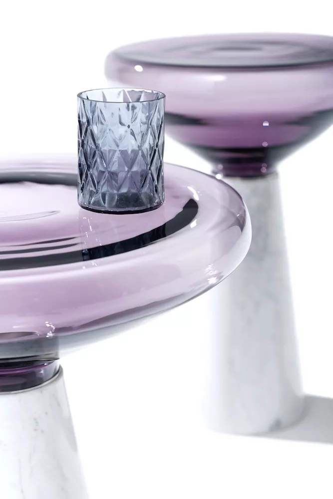Draenert Blow Beistelltisch aus Glas und Marmor mit lila Glasplatte und grauem Glasbecher auf weißem Hintergrund