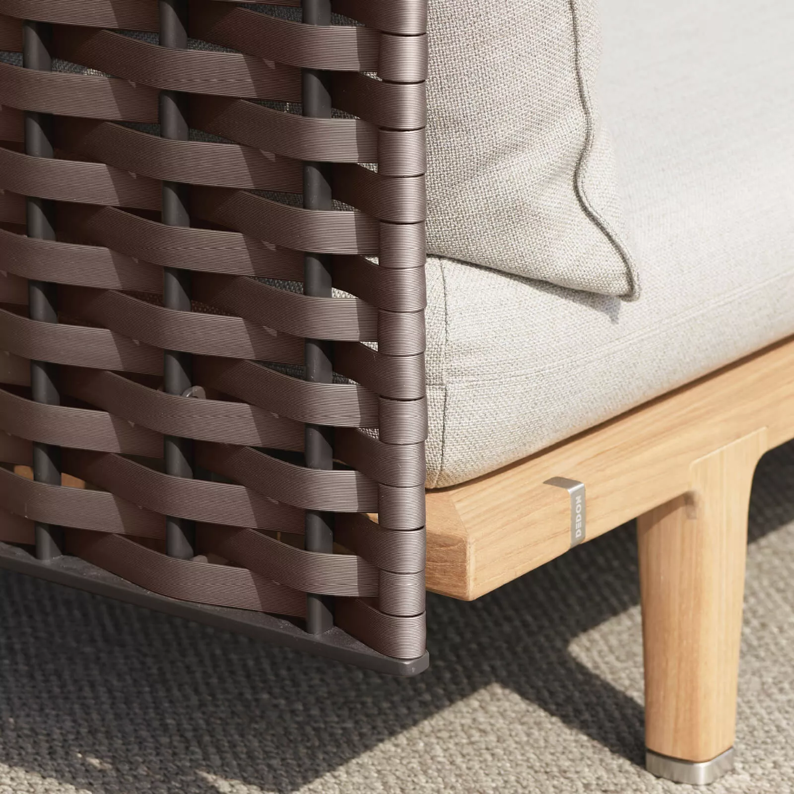 Dedon Sealine Lounge Geflecht Detailansicht eines Loungesessels mit braunem Geflecht und hellem Polster auf einem Holzboden ohne Hintergrund