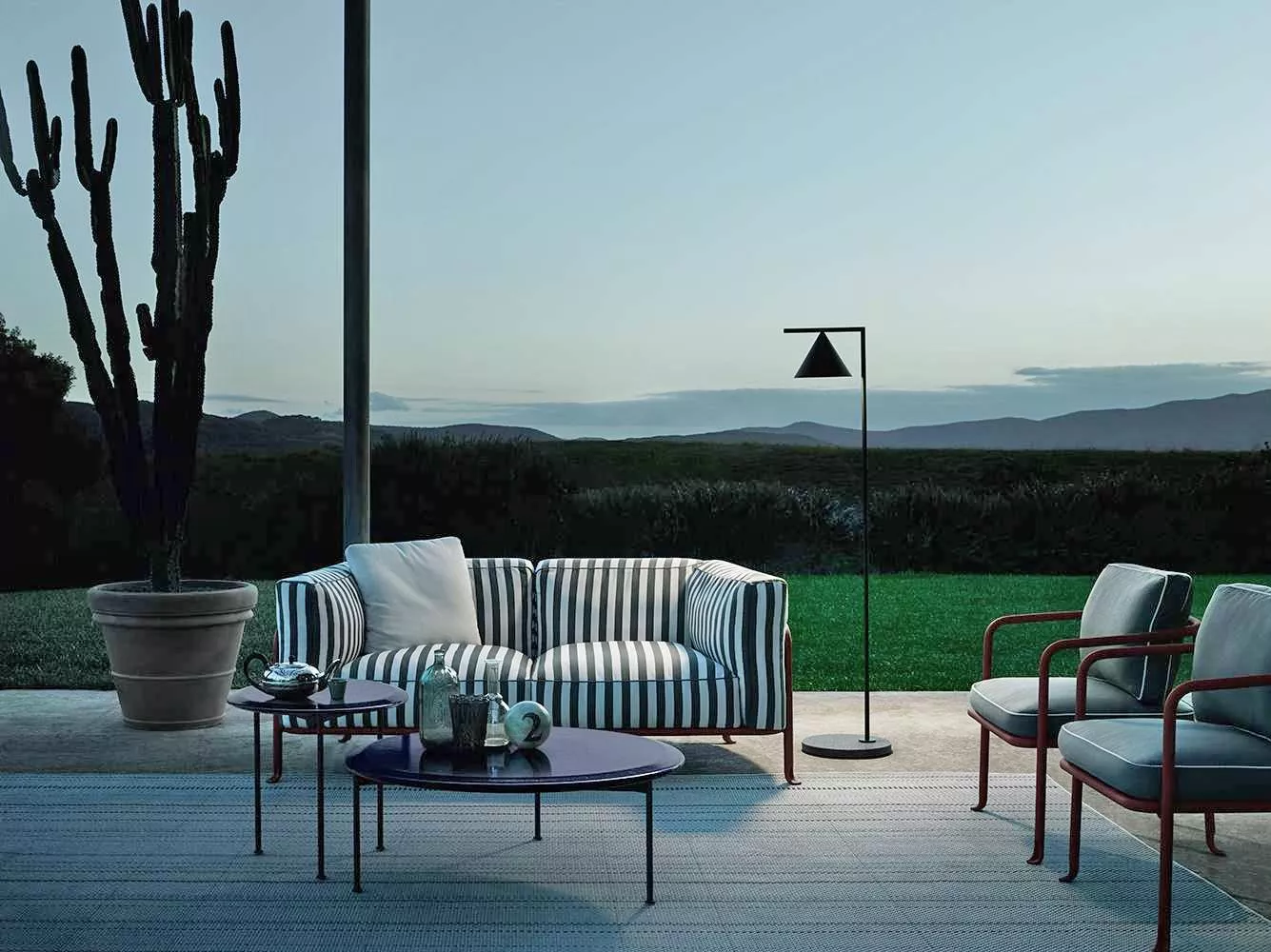 B&B Italia Borea Loungesofa und Sessel in einem stilvollen Outdoor-Setting mit Blick auf die Natur und einem Kaktus im Hintergrund.