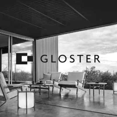Gloster Outdoor-Möbel in modernem Design auf einer Terrasse mit Blick auf die Natur, schwarz-weiß Bild, entspannte Atmosphäre.