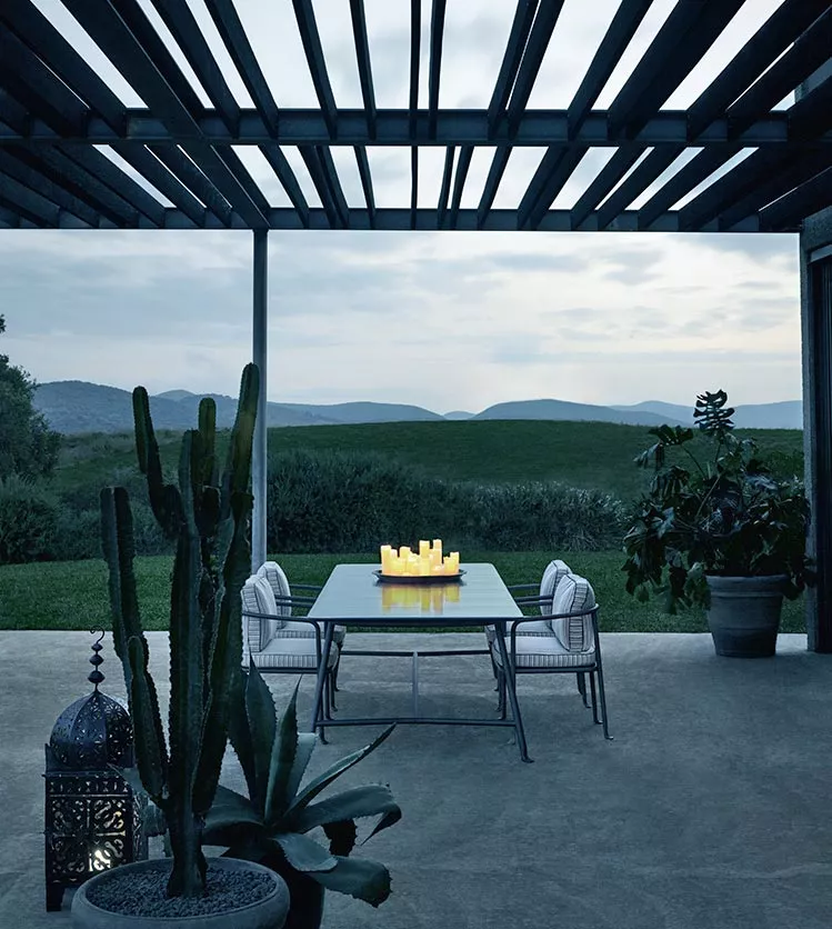 B&B Italia Borea Essgruppe auf einer Terrasse mit Blick auf eine grüne Landschaft und Berge im Hintergrund bei Dämmerung mit Kerzen auf dem Tisch