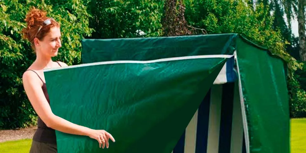 Frau zieht eine grüne Strandkorbhaube von Villa Schmidt über einen Strandkorb im Garten.