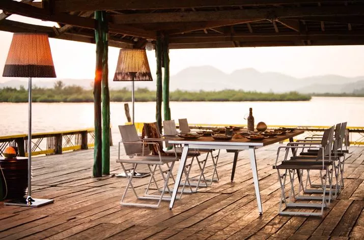 Dedon Seax Kollektion Seax Armlehnstuhl Klappbar Sessel auf einer Terrasse mit Blick auf einen See und Berge im Hintergrund bei Sonnenuntergang