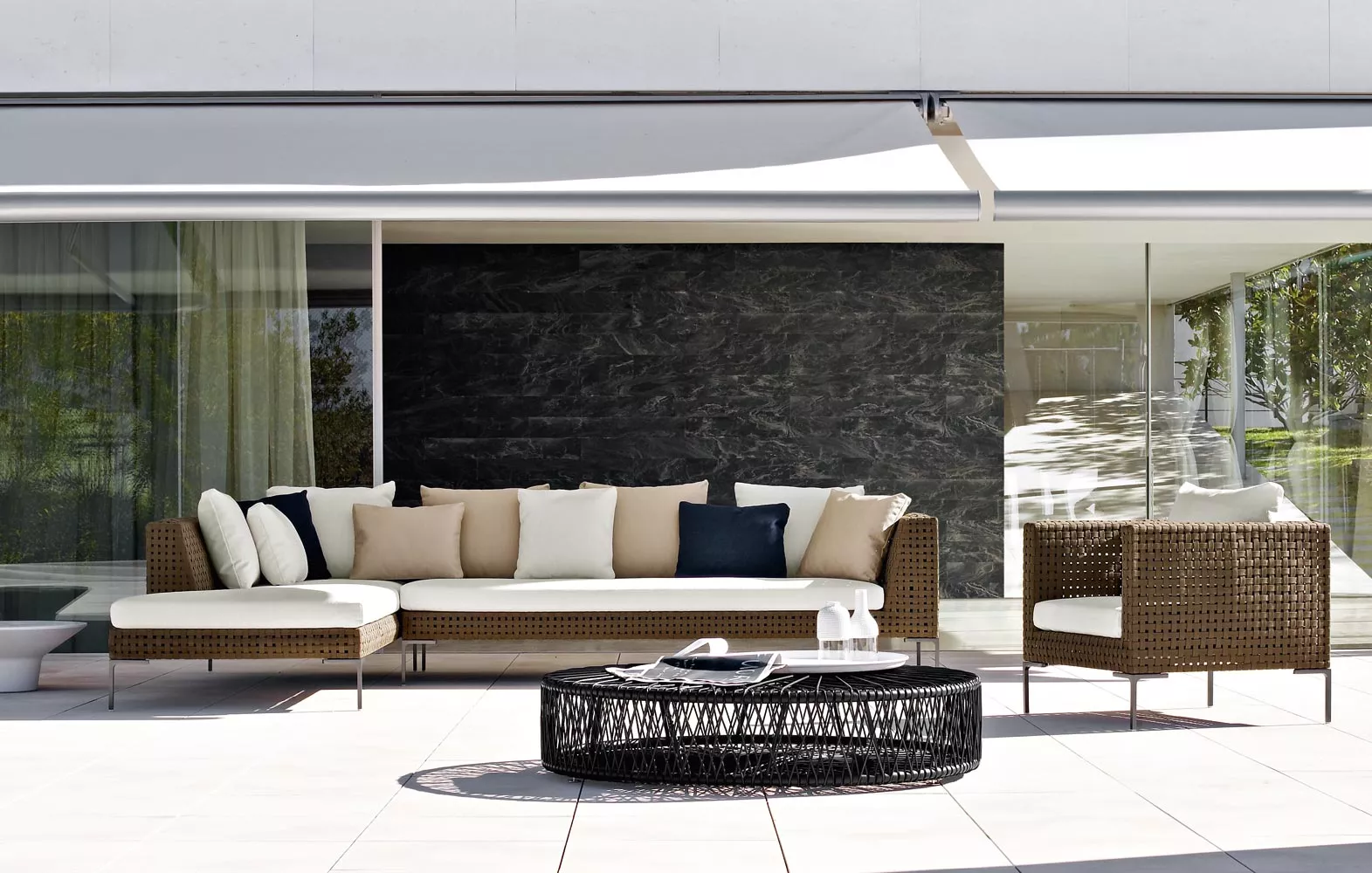 Charles Outdoor Endelement von B&B Italia auf einer Terrasse mit modernen Gartenmöbeln und einem runden Couchtisch in einer sonnigen Umgebung.