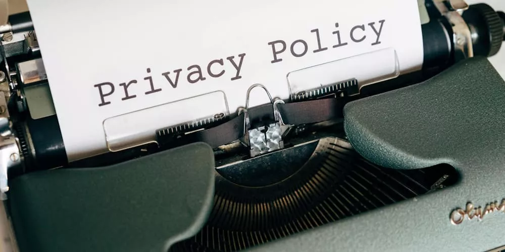 Schwarz-weiße Nahaufnahme einer Schreibmaschine mit dem Text "Privacy Policy" auf dem Papier, im Retro-Stil.