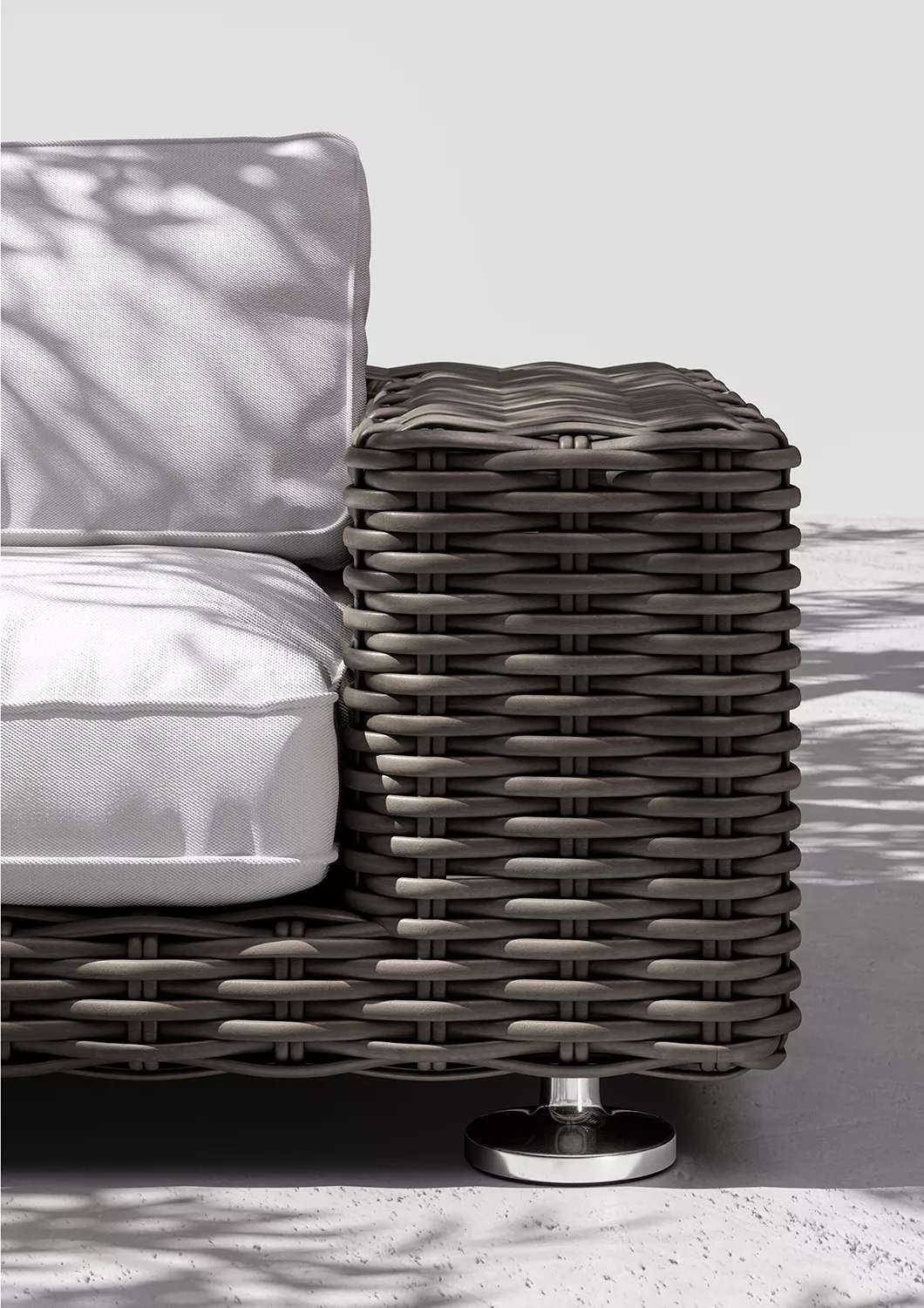 Dedon Paros Sofa in Nahaufnahme mit weißem Kissen und geflochtenem Design im Freien mit Schatten von Blättern auf dem Boden und Sofa