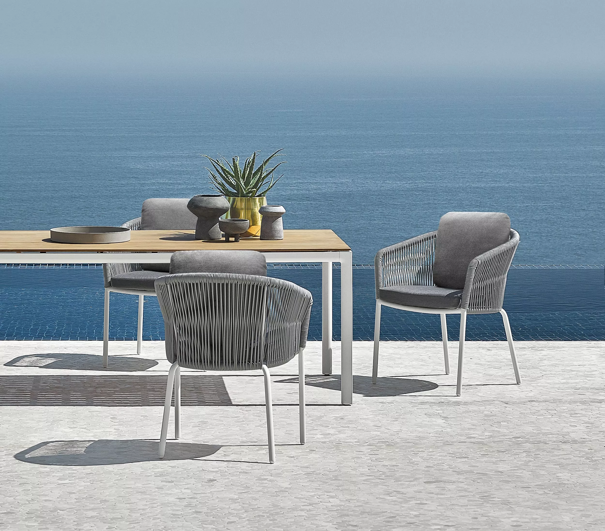 Solpuri Loop Stühle und Tisch auf einer Terrasse mit Blick auf das Meer dekoriert mit Pflanzen und Schalen Moodbild