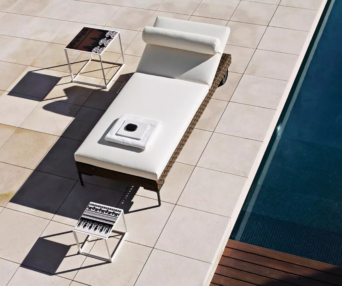 Charles Outdoor von B&B Italia Sonnenliege in Weiß neben einem Pool auf einer Terrasse mit zwei Beistelltischen und einem Handtuch darauf 