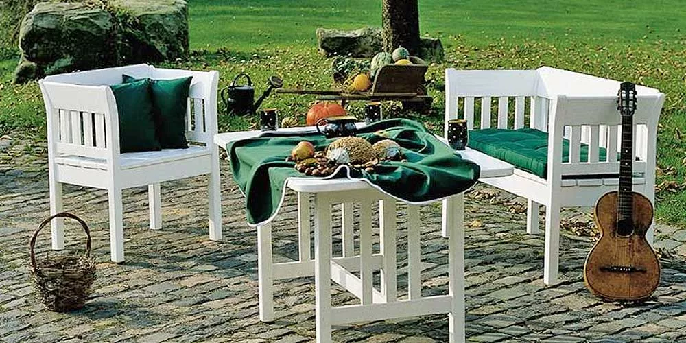 Aerrenhaus Phillipe Essgruppe in Weiß auf Kopfsteinpflaster mit grüner Tischdecke und herbstlicher Dekoration im Garten.